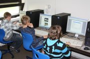 3 Grundschüler sitzen fleißig an den Rechnern im Computerraum
